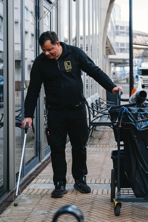 En fastighetsskötare plockar skräp i utemiljön